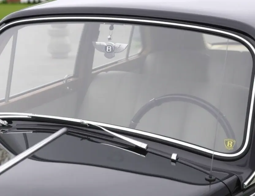 A close-up shot of a Bentley 4½ Litre with a replaced windshield. The windshield should be clear and modern, contrasting with the classic car's design. Focus on the details of the replacement and the car's overall condition.