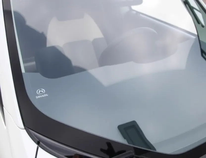 A close-up shot of a Daihatsu Copen with a replaced windshield. The new windshield is clear and seamless, reflecting the surrounding environment. The car is parked on a clean, bright surface. Focus on the windshield replacement detail.