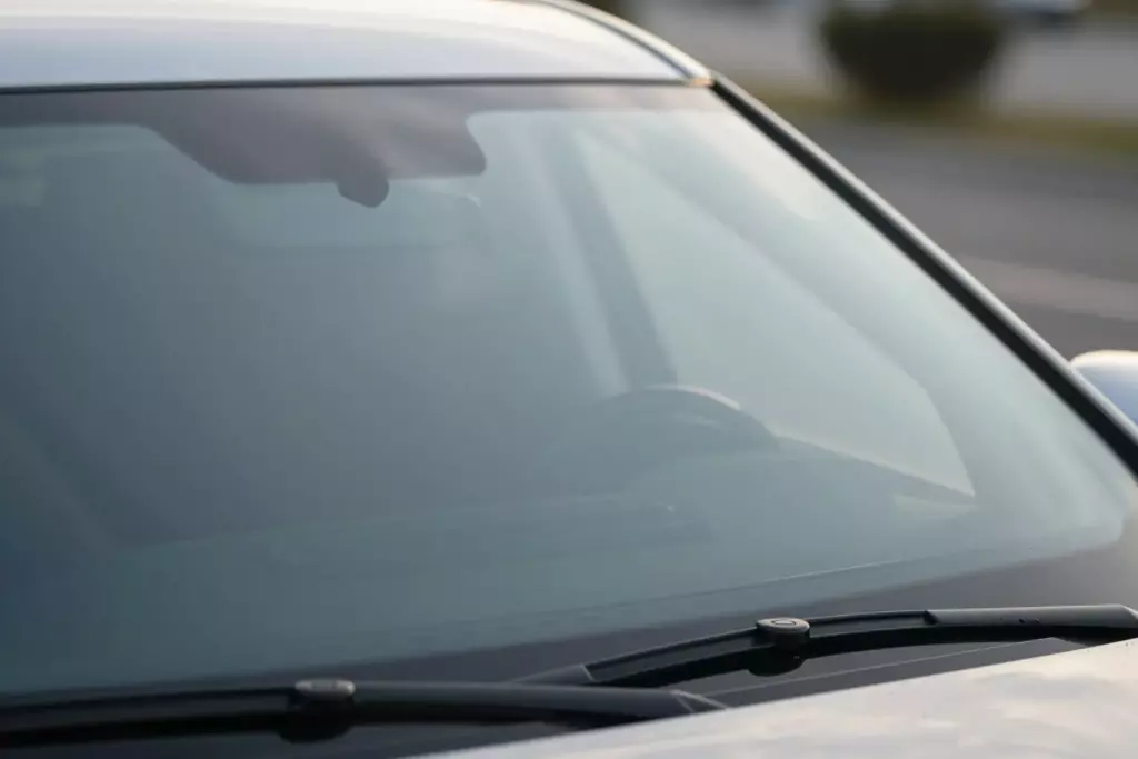 A close-up view of a pristine, clean windshield on a luxury SUV, glistening under soft sunlight, showcasing clarity and high quality, no visible scratches or dirt
