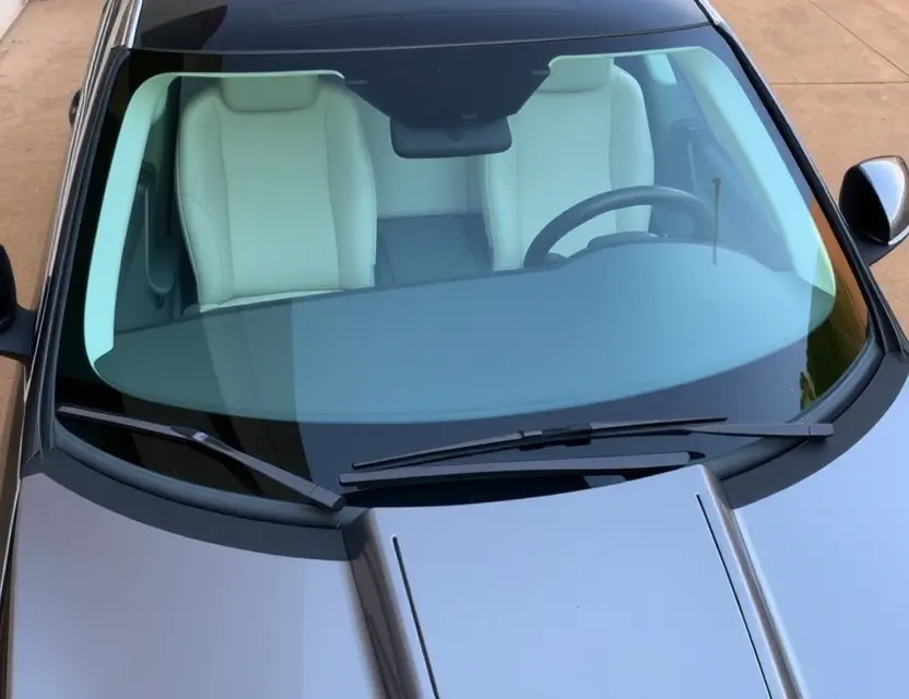 A high-quality image depicting a Jaguar car with a replaced windshield. The windshield is clear and new, seamlessly integrated with the existing frame. The car is parked on a clean, well-lit surface. Focus on the detail of the replacement and the car's sleek design.