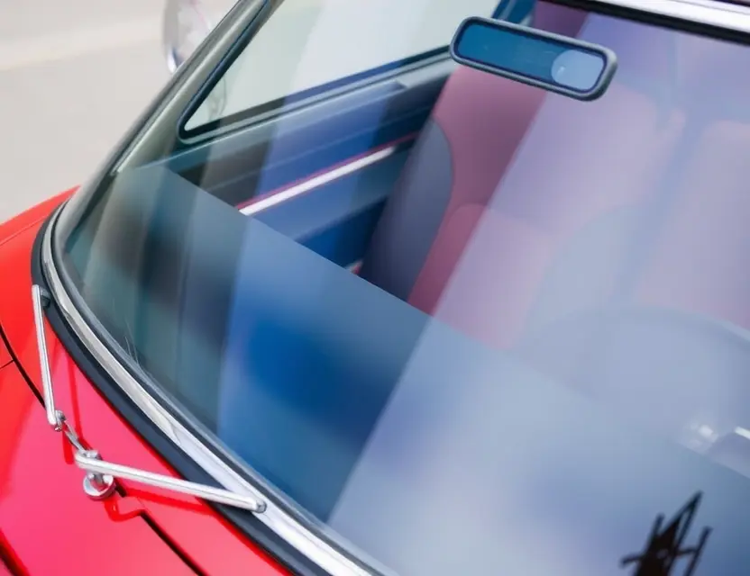 A close-up shot of a Bertone Freeclimber car with a replaced windshield, showcasing the new glass. The car is parked on a clean, modern surface. Focus on the clarity and quality of the replacement windshield.