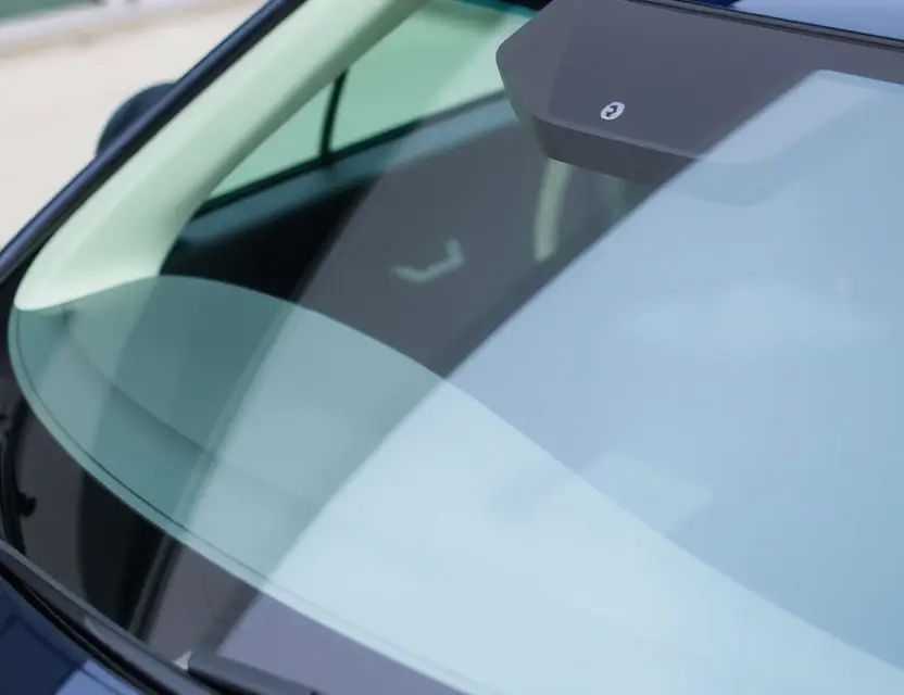 A close-up shot of an Exeed LX car with a replaced windshield. The new windshield is clear and modern, seamlessly integrated with the car's design. Focus on the quality of the replacement and the car's sleek exterior.