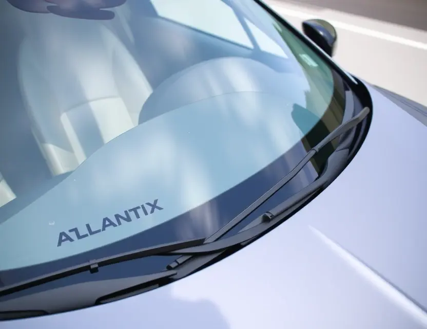 A close-up shot of an Exeed AtlantiX with a replaced windshield, showcasing the new glass. The car is parked on a clean, bright surface. Focus on the clarity and quality of the replacement windshield.